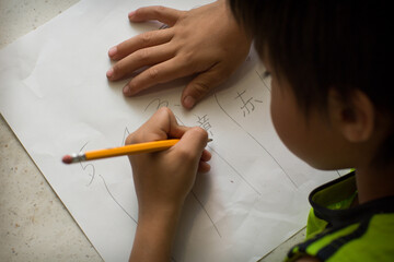A Japanese boy studies Japanese homework in a kitchen.