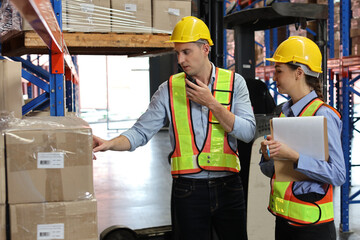 Group of warehouse workers with hardhats and reflective jackets using tablet, walkie talkie radio...