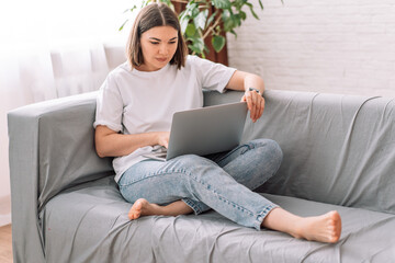 Lady sitting on the couch working on a laptop.