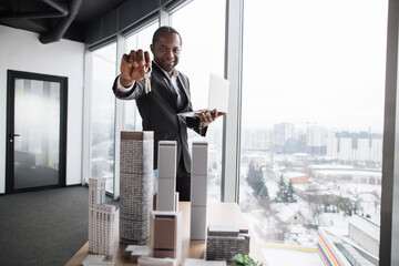 Focus on face of real estate african american manager homeowner businessman banker salesman successful man sell house property hold keys from new apartment near 3d city model at office