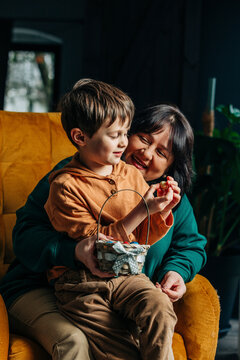 Happy grandmother with grandson holding Easter chocolate eggs sitting on armchair