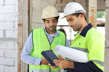 Two technician civil engineer or specialist inspector discussing, brainstorm and planing work with tablet, blueprint and walkie talkie radio together at Industrial building site. Construction concept