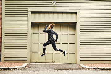 Female runner jumping while doing warming up exercises, Boston, Massachusetts, USA