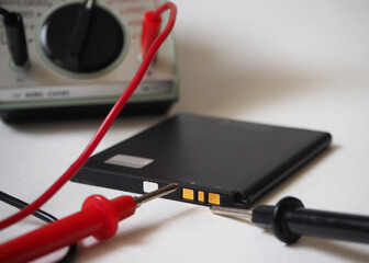 Lithium battery test with voltmeter. Cell phone battery. Focused on battery poles.