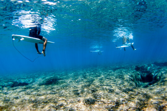 Underwater view of surfers above reef at Pipeline, on North Shore of Oahu, Hawaii, USA