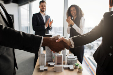 Selective focus on hands of two business people handshake after successful deal, colleagues businesspeople real estate, agents developers applauding, city district urban planning project good work.