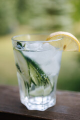 Gin tonic in glass. Mojito coctail. Decorated by a slice of lemon and. Wooden table