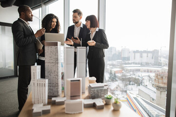 Business, company strategy, financial report concept. Team of diverse multiethnic businesspeople working with financial reports using laptop at open space office with white walls and panoramic windows