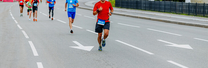 Fototapeta na wymiar man runner leads group of runners city marathon race