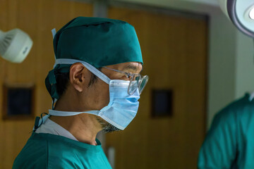 male asian doctor working operating room. professional surgical asian guy wearing mask doing surgery to save patient life in operating room. male nurse wearing mask performing in emergency operation