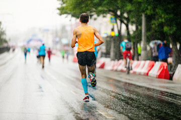 back runner athlete run in rain on road city marathon