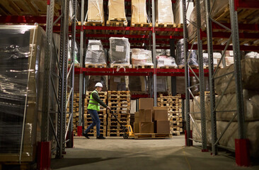 Side view view at storage warehouse interior with worker pushing cart in aisle, copy space