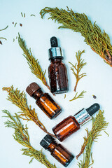 Juniper essential oil in a glass bottle on a white table. The concept of herbal medicine, spa, aromatherapy and body care. Heather essential oil in an amber bottle. Selective focus.