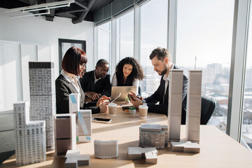 Business team of four good-looking multiethnic corporate workers discussing financial report using...