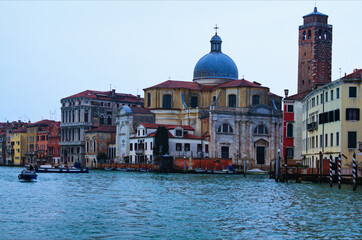 Picturesque panoramic view over Grand Canal in Venice. Moored boats near colorful ancient buildings.  Winter drizzle morning in Venice. Famous touristic place and travel destination in Europe