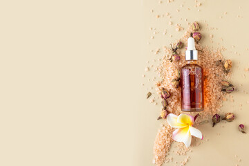 Holistic skin care still life composition. Essential oil bottle; salt scrab; rosef and rangipani flower; on beige background.Spa and auyrveda beauty centre