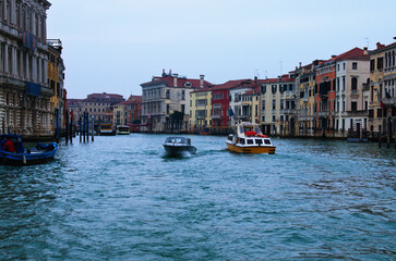 Amazing panoramic view over Grand Canal in Venice. Moored boats near colorful ancient buildings.  Winter drizzle morning in Venice. Famous touristic place and travel destination in Europe