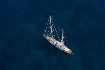Big wooden sailing yacht on dark water aerial view. Mega sailing yacht in the sea at the anchorage...
