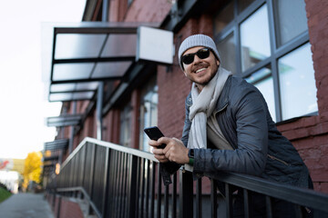 stylish young man outside in sunglasses with a phone in his hands