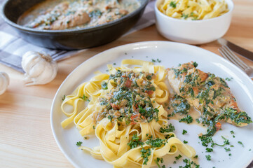 Chicken breast with pasta and spinach cream sauce on a plate on kitchen table