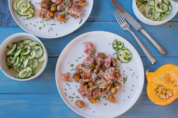 Pan fried pumpkin gnocchi with ham, cheese and herbs on blue wooden background