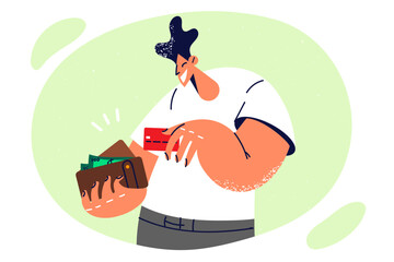 Positive man with wallet filled with banknotes takes out credit card to pay in store after shopping