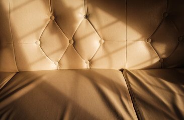 closeup photo of leather chair with sunlight reflecting and shadows of the window