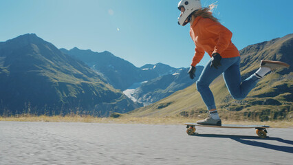 Cinematic downhill longboard session. Young woman skateboarding and making tricks between the curves on a mountain pass. Concept about extreme sports and people