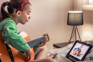 Little girl learns to play the guitar, online music video lesson.