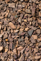 Closeup Image of Background Made of Pile of Colorful Brown, Yellow and Red Crushed Stones. Vertical Shot - obrazy, fototapety, plakaty