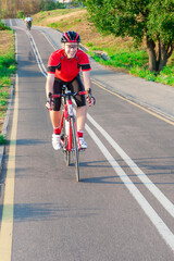 Obraz premium Road Cycling. One Emotional Male Cyclist Riding Road Bike Uphill Equipped with Summer Bike Outfit Posing Outdoor During Training.