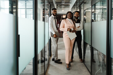 Young multiracial people smiling while standing at office corridor