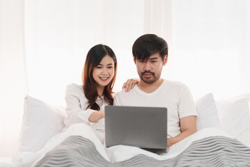 Beautiful asian couple in love and smiling sitting on bed. Romantic moment, relationships, family concept.
