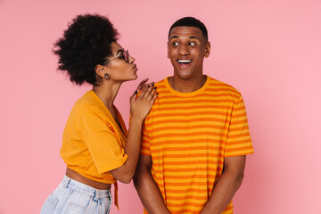 African woman kissing her boyfriend isolated over pink wall