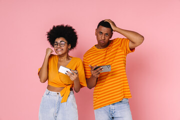Afro woman making winner gesture while playing online game with upset man isolated