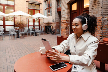 African american woman using tablet computer and headphones in cafe