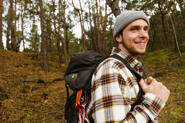 Young smiling man tourist hiking in forest