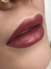 permanent makeup on the lips of a young woman of a delicate peach shade close-up, a girl after a...