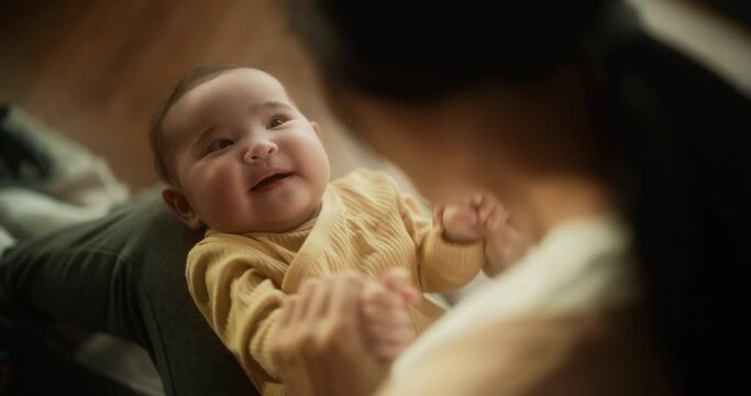 Portrait of a Cute Asian Baby Laughing, Resting on Her Mother's Lap and Enjoying a Bonding Time Together, Looking at her with Love. Playful Mom Tickeling her Toddler and Playing with Her