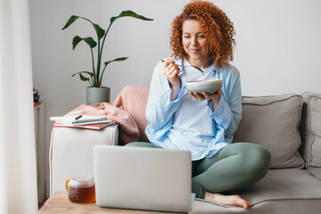 Indoor image of pretty cute woman in home clothes watching series on laptop sitting on sofa with...