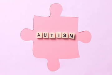 Autism lettering in squares isolated on pink background in puzzle shape. World Autism Awareness Day.