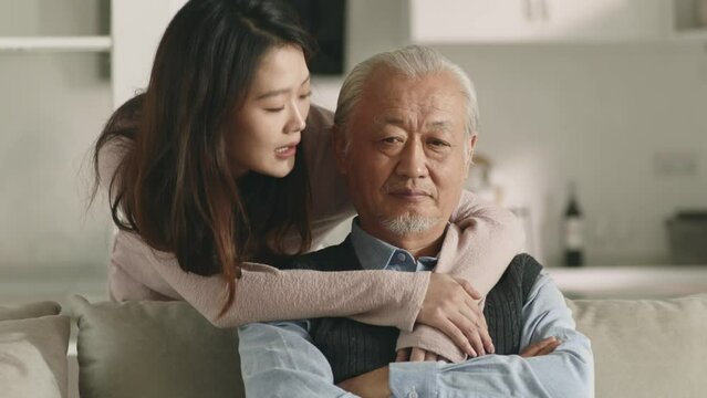 young asian loving and caring adult daughter consoling sad senior father at home