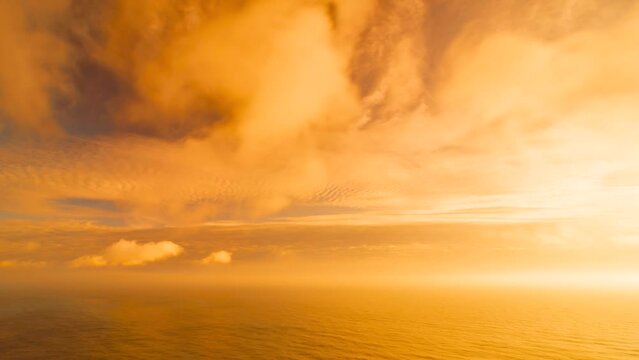 Timelapse of bright sunset, fluffy clouds moving in golden burning sky over sea. Abstract aerial nature summer ocean sunset, sea and sky background. Vacation, travel, holiday concept. Aerial view