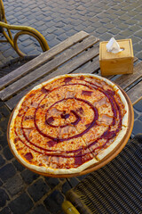 pizza on a wooden table of a street cafe on a summer day