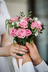 Obraz na płótnie Canvas Bouquet of white and pink of roses in bride's hands. Newlywed couple. Groom and bride together. Perfect wedding couple holding a luxury bouquet of flowers. Close up.