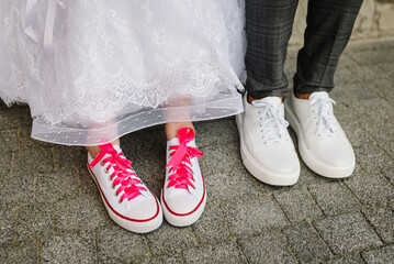 The bride and groom wearing pink sneakers. Concept funny wedding couple. The newlywed together....