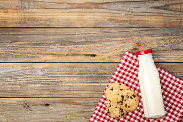 Bottle of milk and cookies on a wooden background, top view.