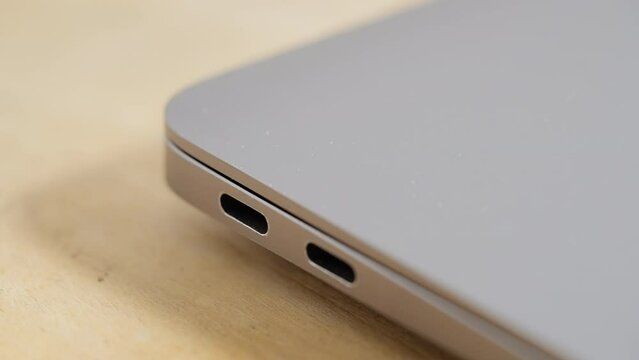 Close up, unplugging USB-C cable from silver laptop on a desk
