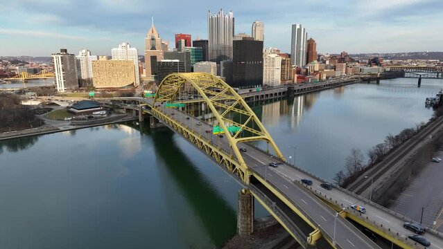 Pittsburgh skyline behind Fort Pitt Bridge over Monongahela River in Pennsylvania. Aerial rising establishing shot of Pittsburgh PA on sunny winter day.