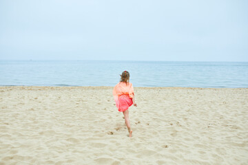 Fototapeta na wymiar Happy, joyful little girl run on the beach